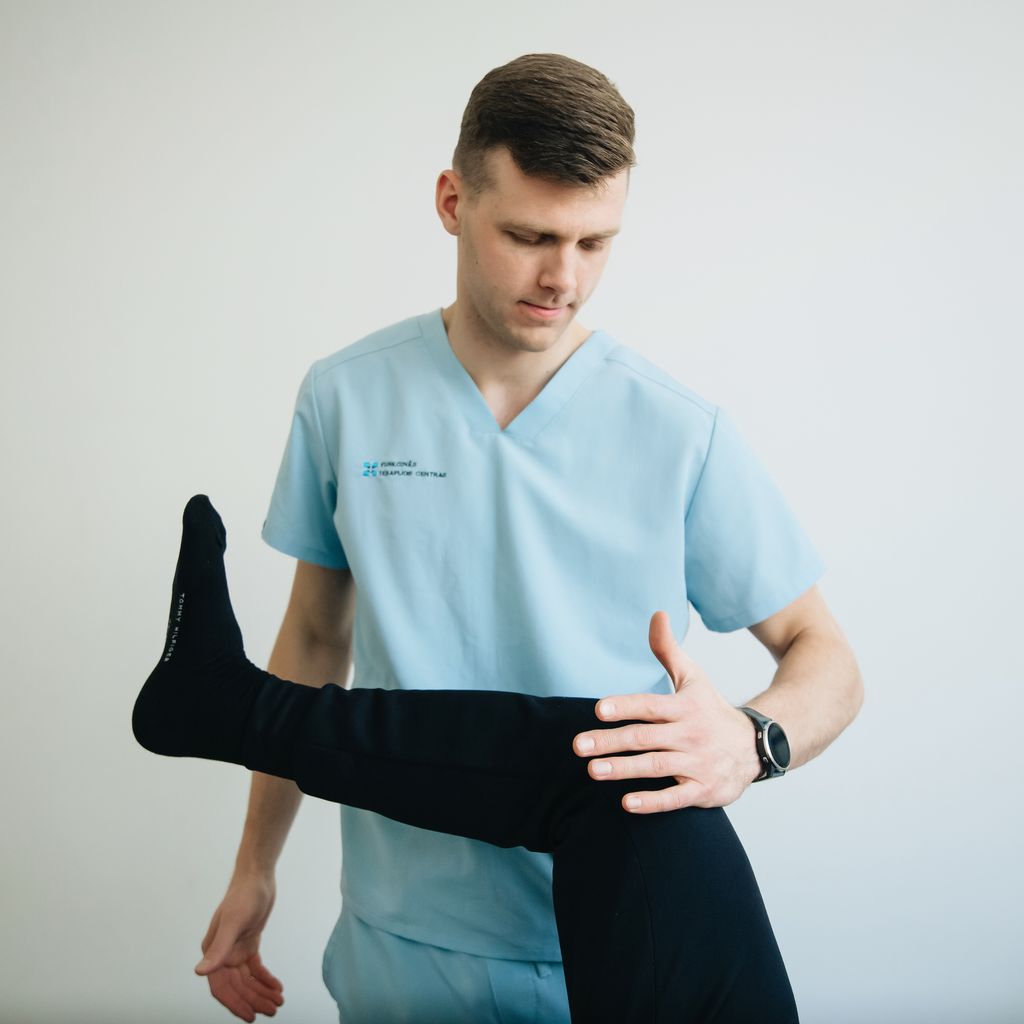 A physiotherapist assists a patient with knee pain treatment in a clinical setting.